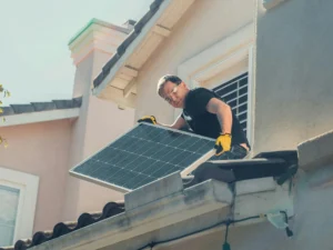 Technician installing a solar panel on a residential home rooftop for clean energy generation