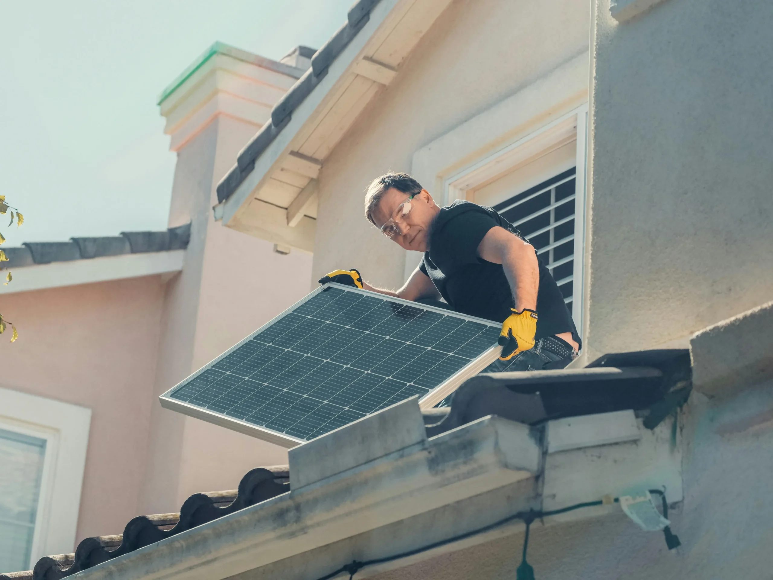 Technician installing a solar panel on a residential home rooftop for clean energy generation